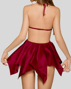 Woman wearing red luxury silk nightwear with lace details and halter neck on gray background