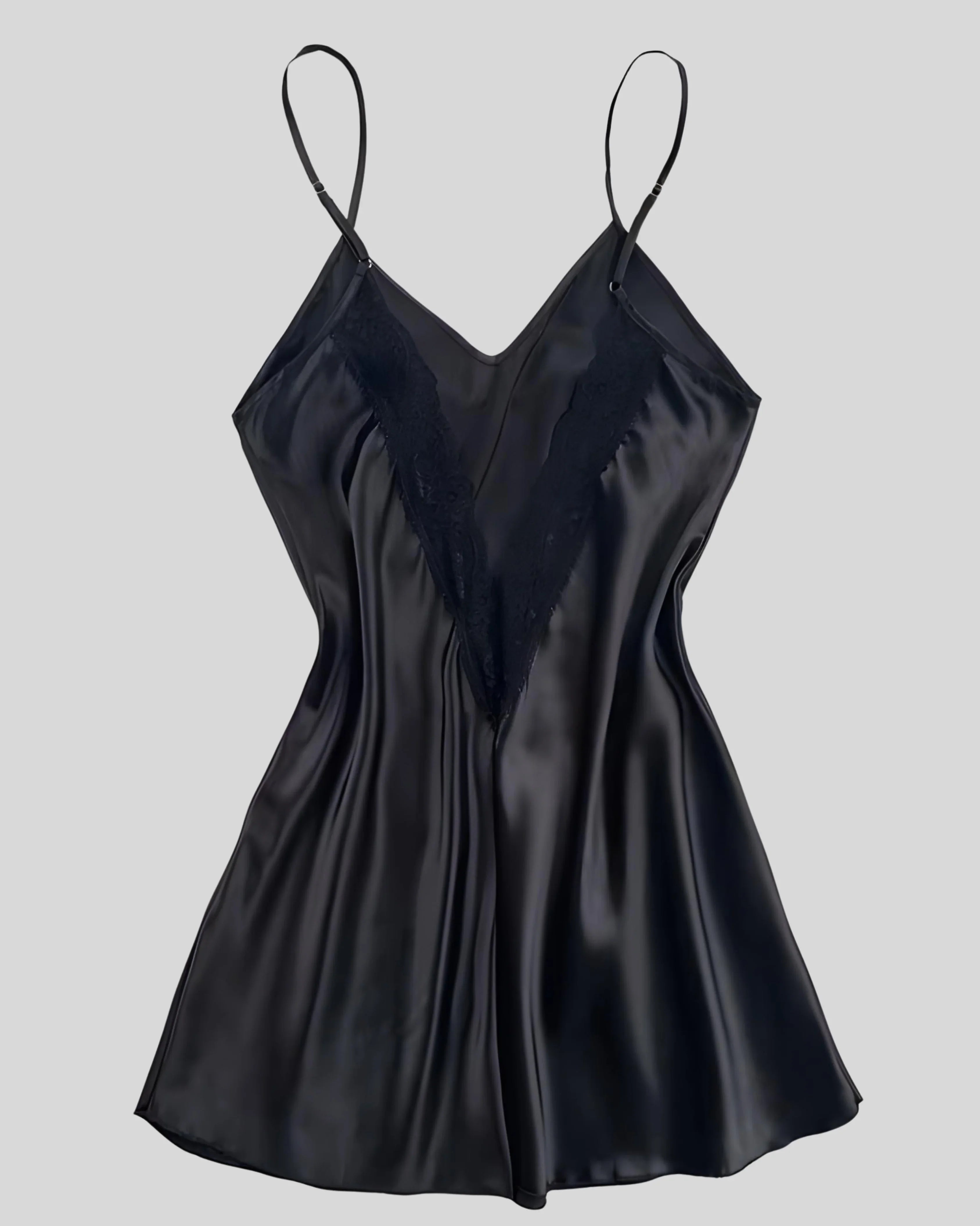 Woman wearing a black silk slip dress with thin straps, accessorized with gold chain necklace and bracelets on gray background